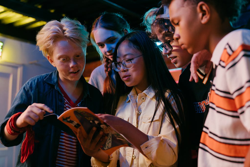 A diverse group of teenagers enthusiastically reading a book indoors, showcasing friendship and learning.