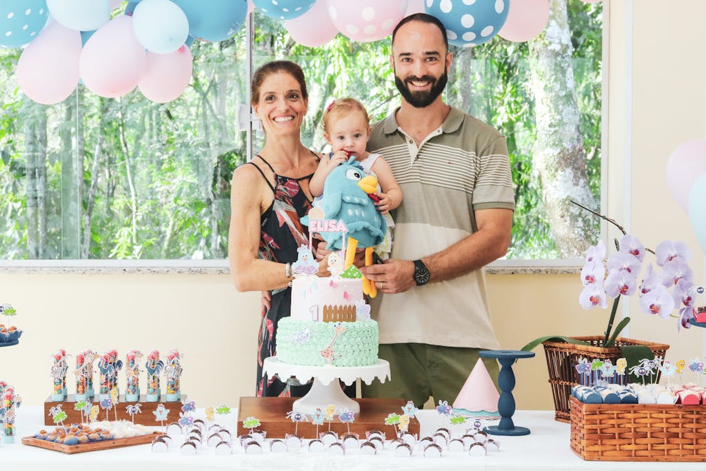 A joyful family celebrates a child's first birthday with decorations and cake.