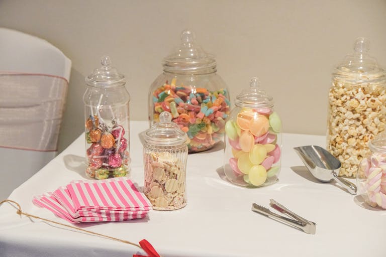Colorful candy jars with sweets and popcorn on a table, ready for a party.