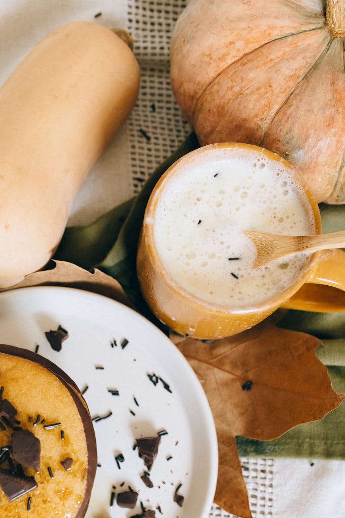 Cozy autumn setting with a pumpkin latte, squash, and dessert, perfect for a fall vibe.