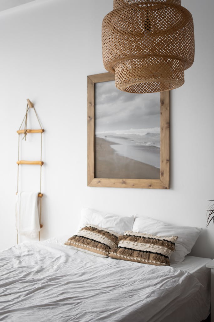 Elegant bedroom with rattan chandelier and coastal wall art creating a serene atmosphere.