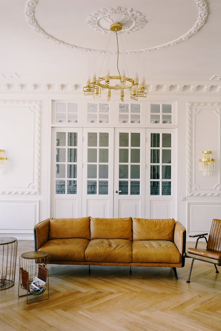 Luxurious interior design featuring a leather couch, chandelier, and white walls.