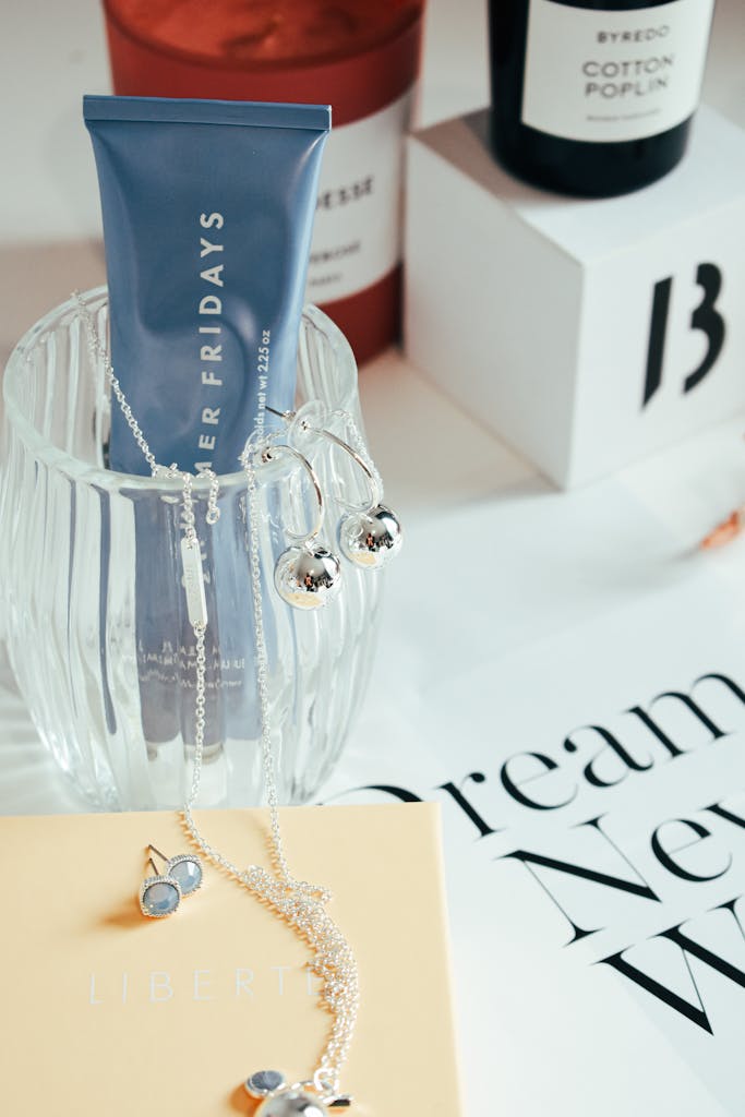 Stylish arrangement featuring a skincare tube with elegant jewelry on a decorative table.