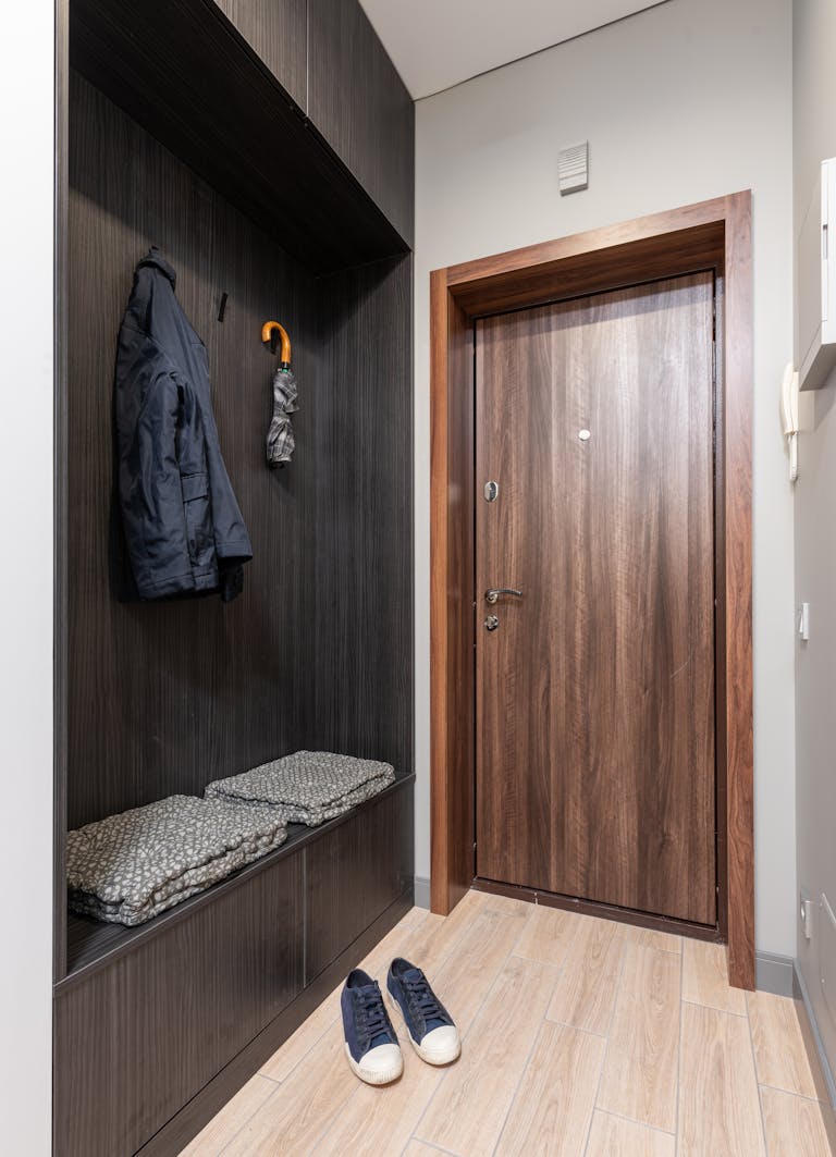 Stylish minimalistic entryway featuring wooden decor and organized storage solutions.