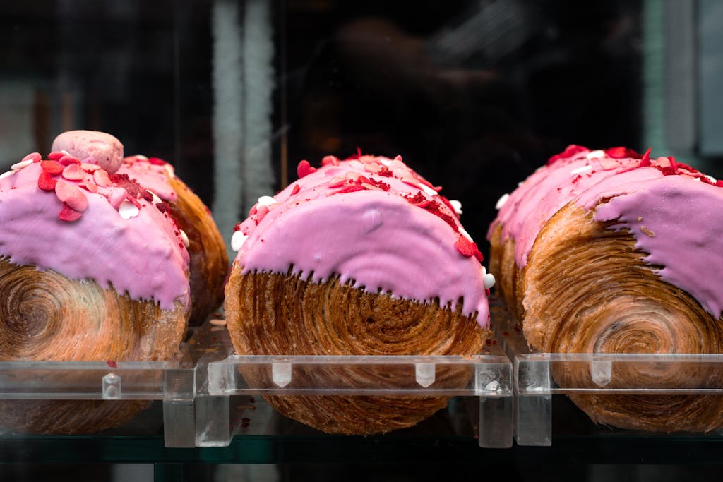 Tempting pink-frosted croissants with heart sprinkles on display in a São Paulo bakery.