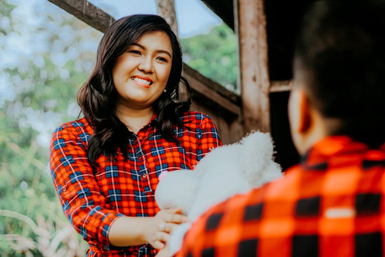 Woman giving a teddy bear to a man outdoors, capturing a joyful and loving moment.