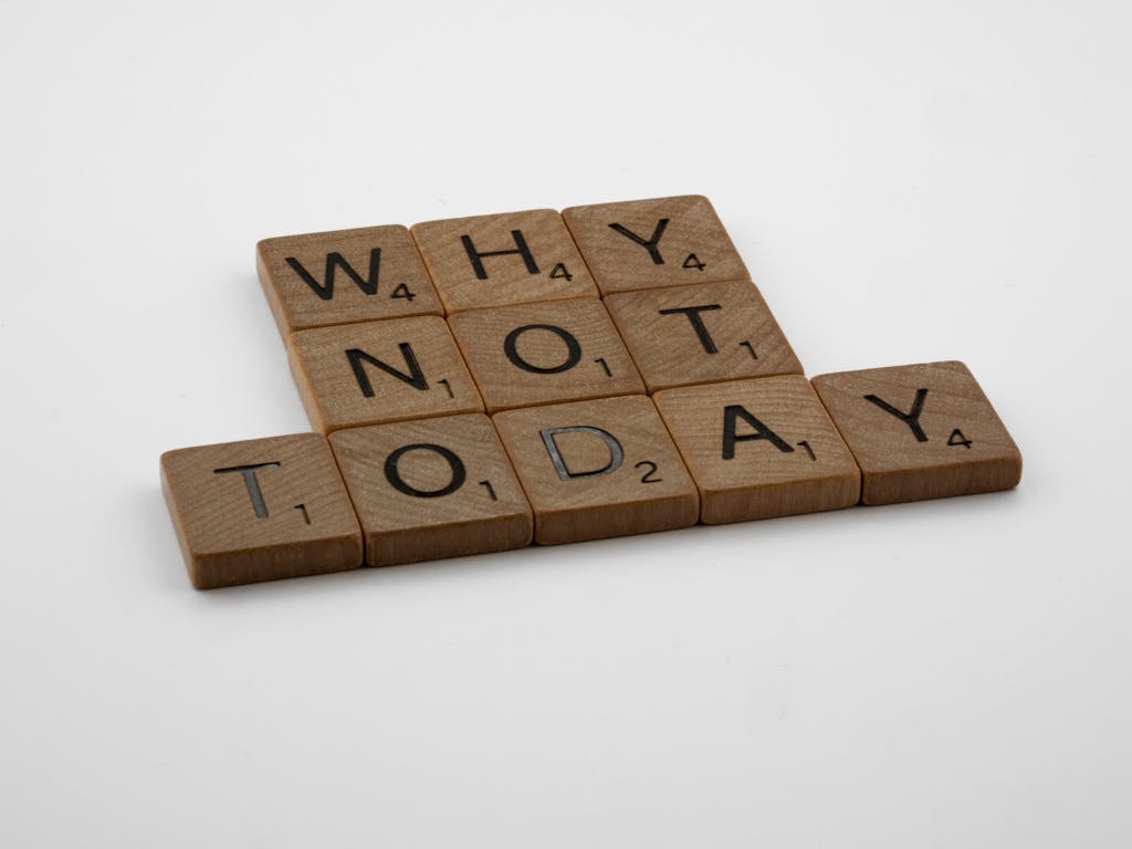 Wooden scrabble tiles arranged to form a motivational message on a white background.