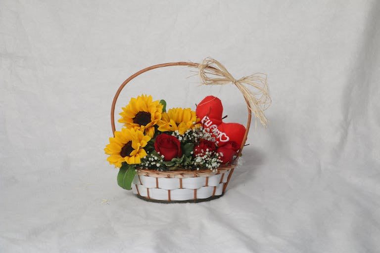 Charming flower basket with sunflowers, roses, and decorative hearts perfect for celebrations.