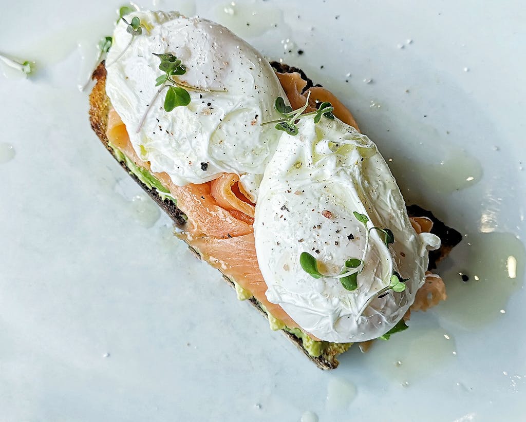 Delicious poached eggs with smoked salmon and herbs on toast. Perfect breakfast option.