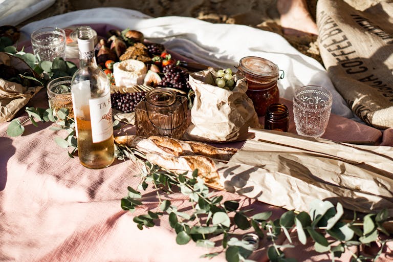 A picturesque outdoor picnic featuring a wine bottle, assorted snacks, and rustic decor for a perfect gathering.