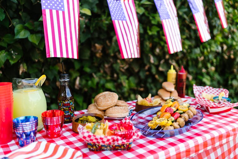 Colorful picnic setup celebrating Fourth of July with American flags, food, and drinks.