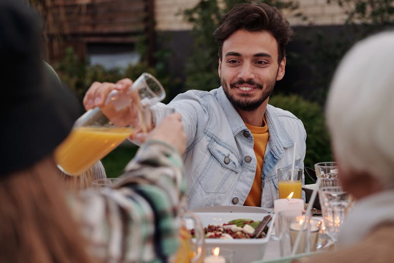Joyful outdoor dinner gathering with friends and family enjoying meals and beverages.