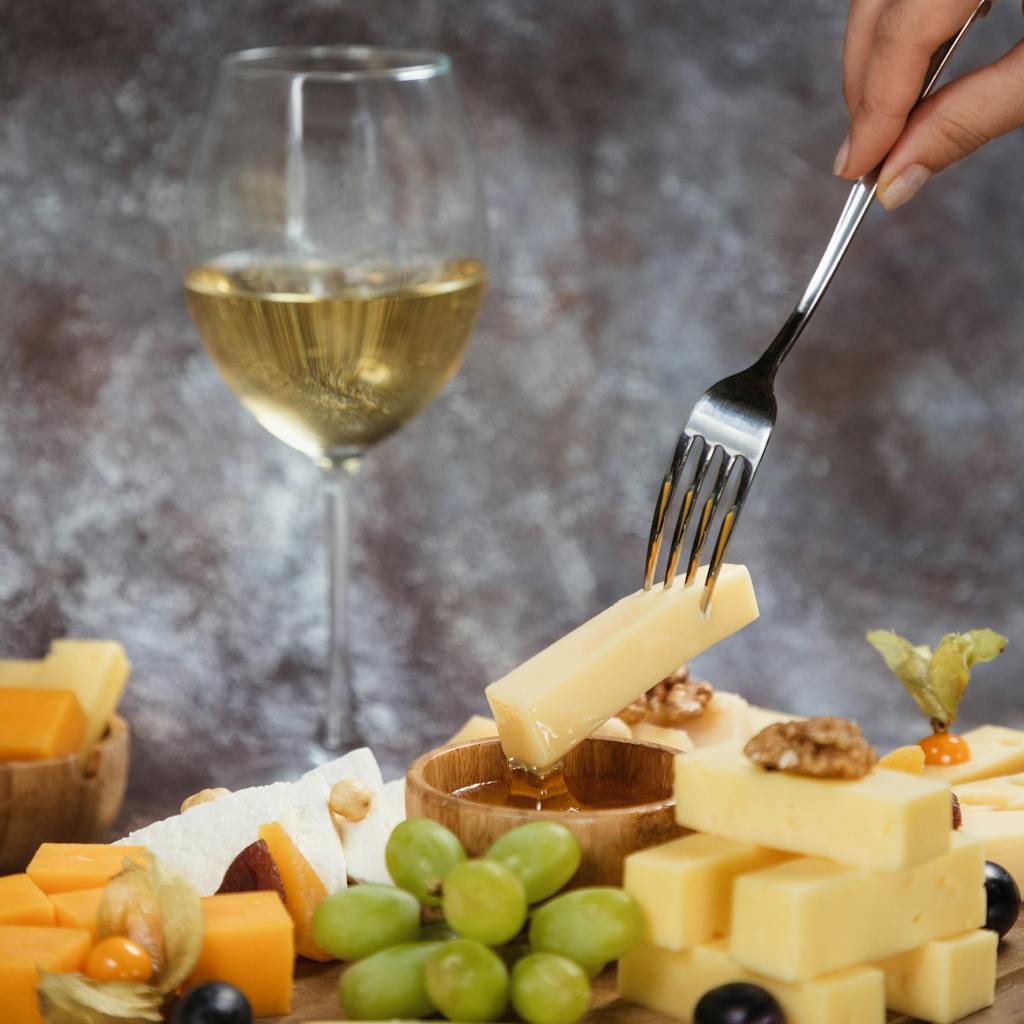A gourmet cheese platter paired with white wine, featuring grapes and nuts for an exquisite dining experience.