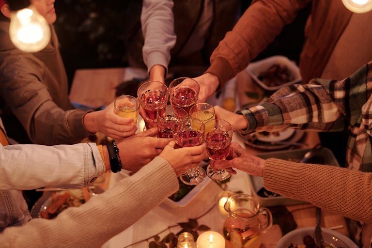 A warm gathering of friends toasting with glasses of wine over a candlelit dinner table.
