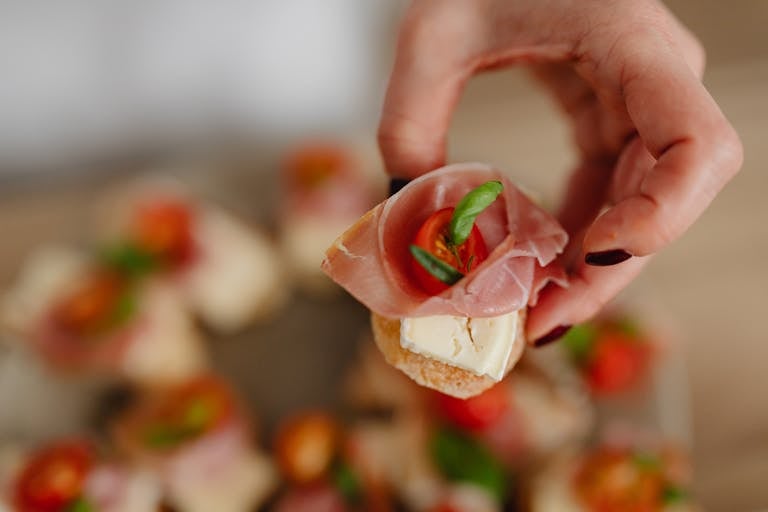 Appetizing hand-held tapas with cheese, cured meat, and a touch of basil.