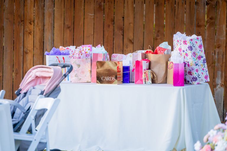 A table filled with colorful gift bags and a stroller at an outdoor event.