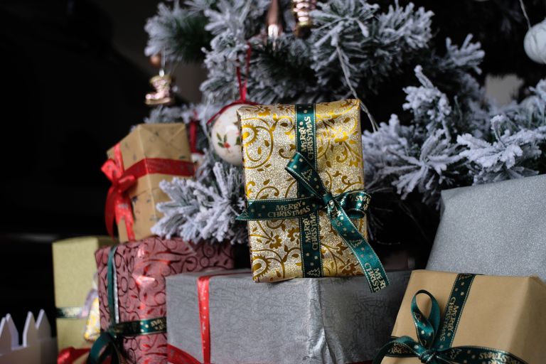Beautifully wrapped gifts under a snow-flocked Christmas tree, perfect for holiday decor inspiration.
