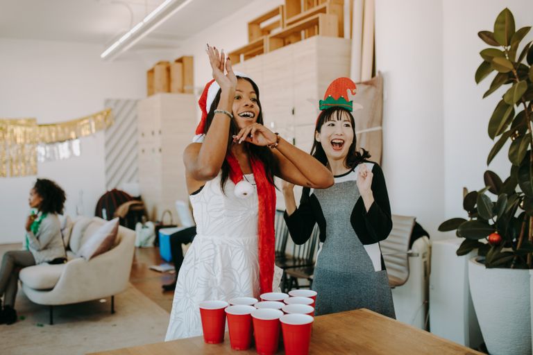 Adults enjoying a fun Christmas party with festive games and decorations in an office setting.