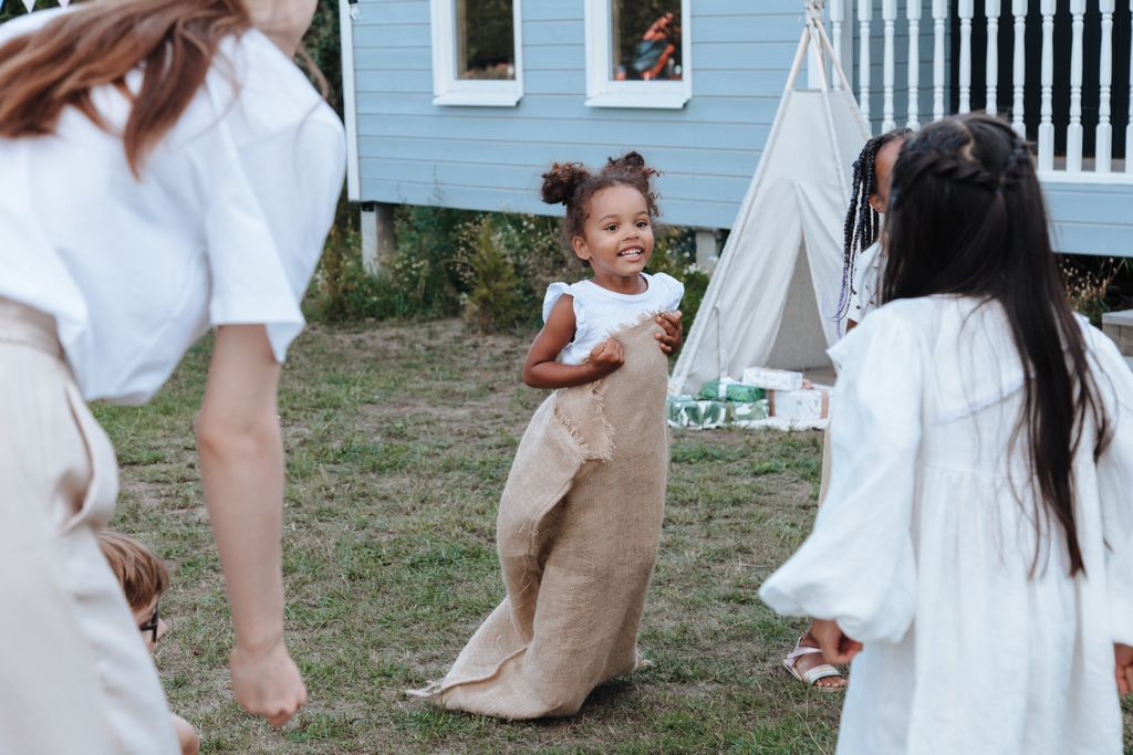 Children enjoying a fun sack race outdoors amid party vibes and cheerful laughter.